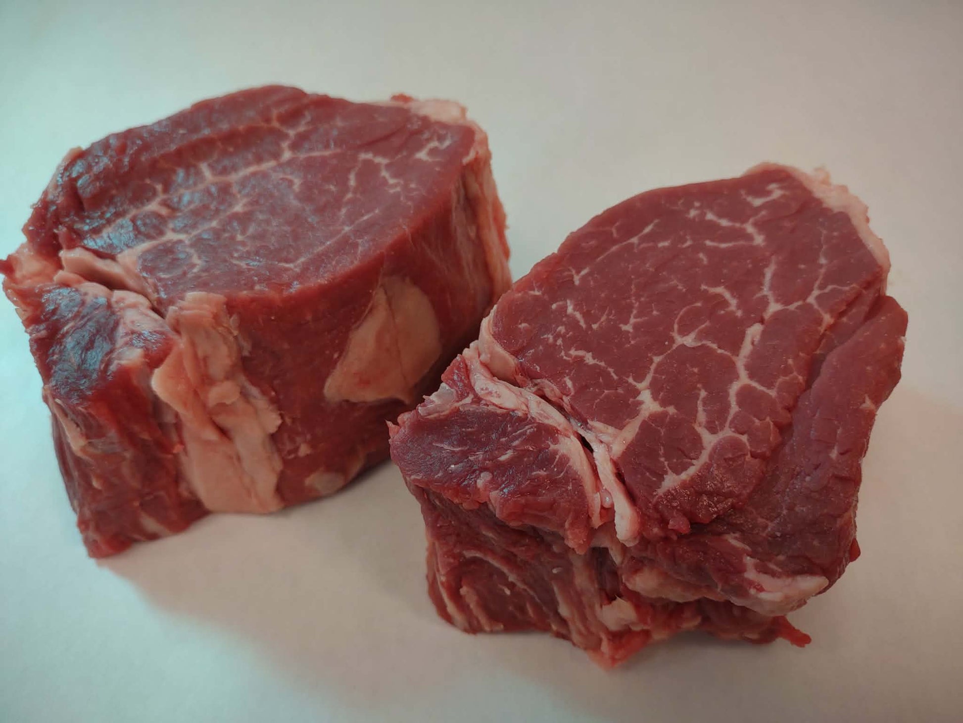 Two pieces of raw  local Beef Filets on a white surface